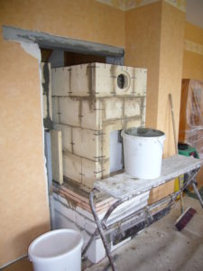 Der Grundofen wird durch die Dielen- Wohnraumwand gebaut und erwärmt so später die beiden Räume.